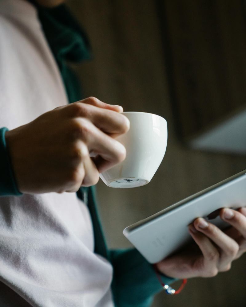 Person hält Tasse und iPad in der Hand